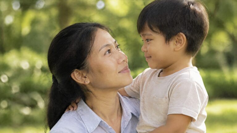 Carrie holders her young son in her arms. They're smiling at each other.